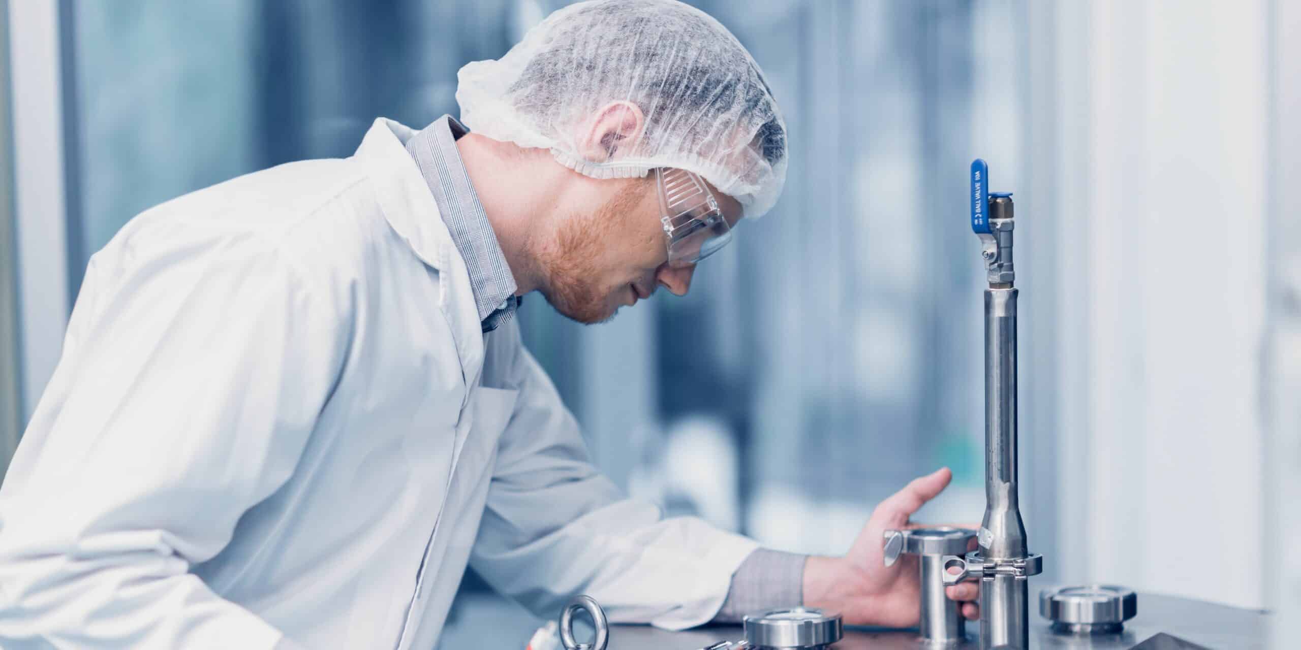A man wearing a lab gown checking a water tank